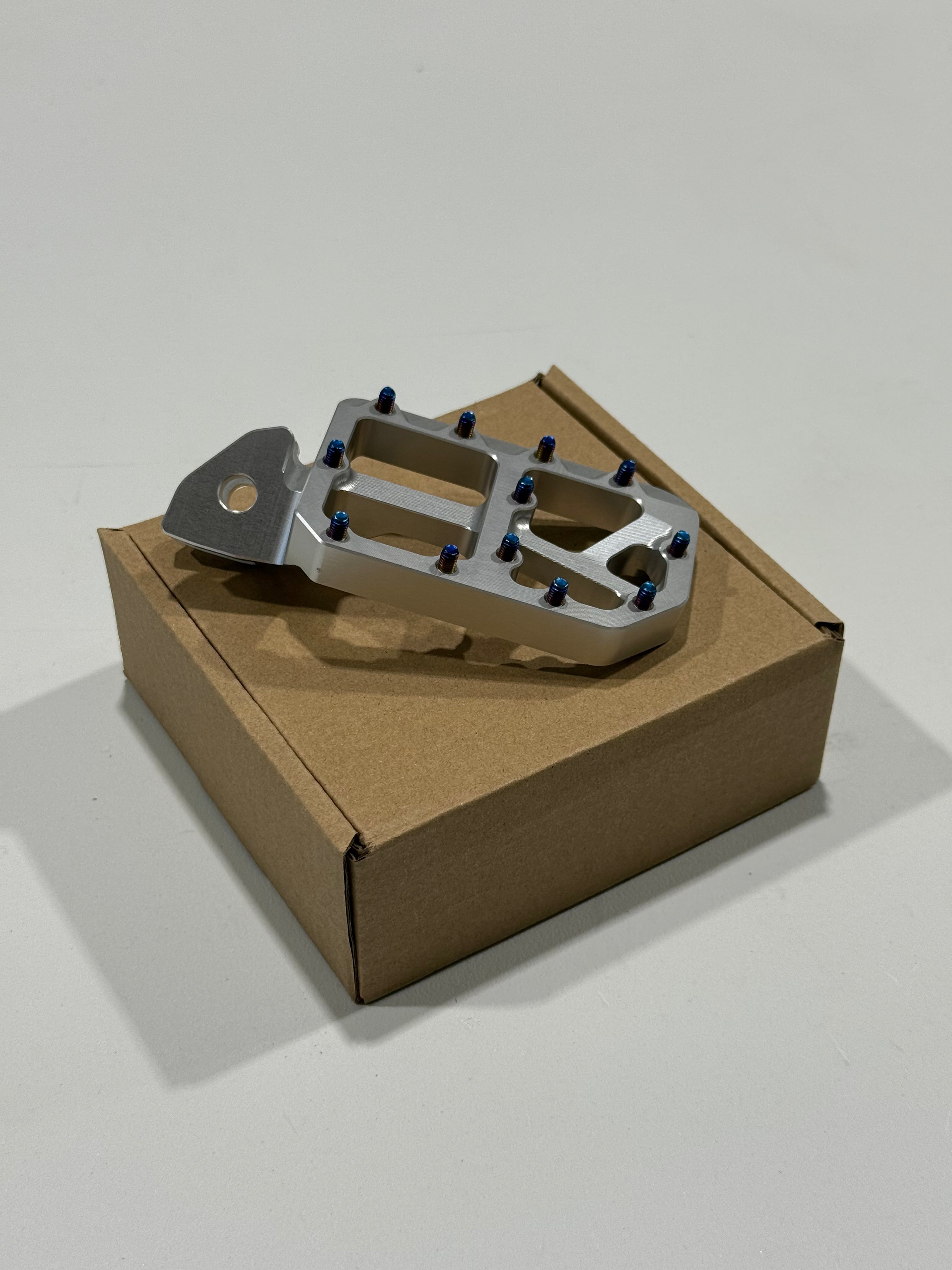 E-moto wide foot pegs showing aggressive grip teeth