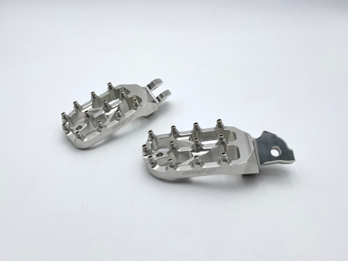 White anodized Warp 9 Elite foot pegs for the Talaria Sting