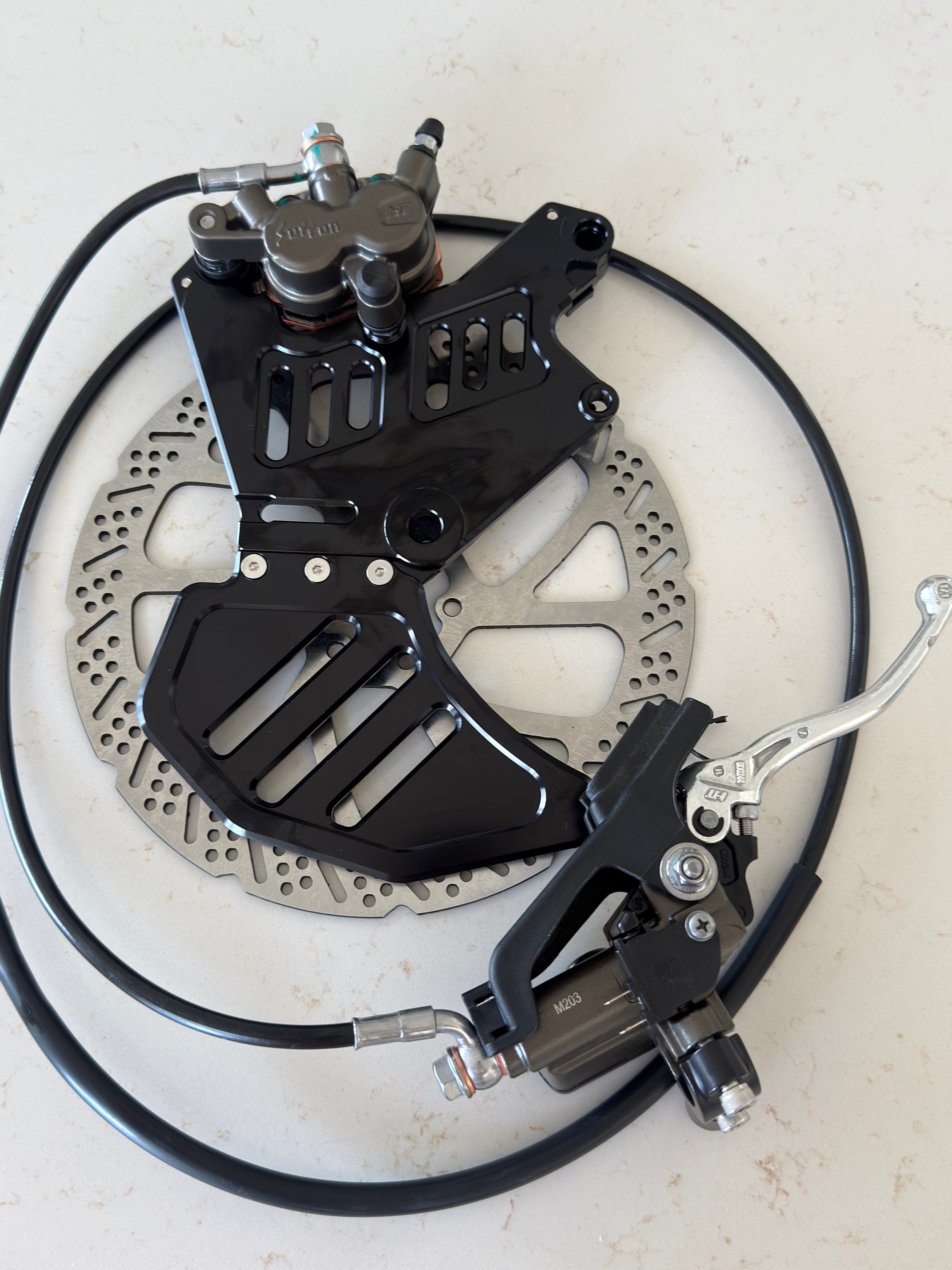 Complete rear moto brake kit components laid out for the Sur-Ron and E-Ride Pro