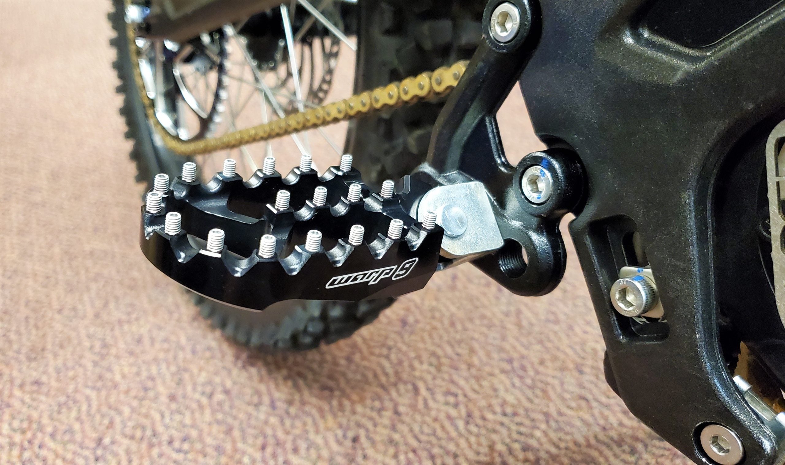 Warp 9 foot pegs bolted onto a Sur-Ron Light Bee frame mount